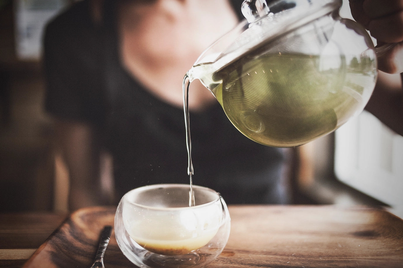 une jeune femme versant du thé vert dans sa tasse